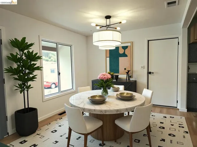 Bright dining area featuring a circular marble-top table, wood-finish flooring, and a contemporary chandelier. Virtual Staging.