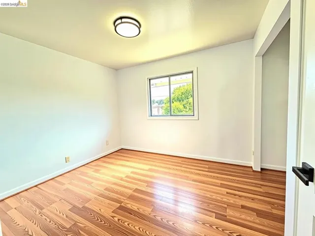 Room with wood-finish flooring, white walls, and a recessed window