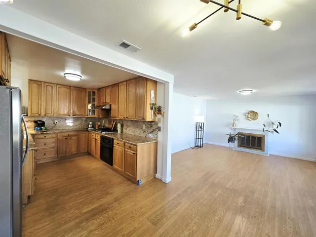 Spacious open-concept living area featuring a kitchen with wood cabinetry, stone countertops, and a full backsplash
