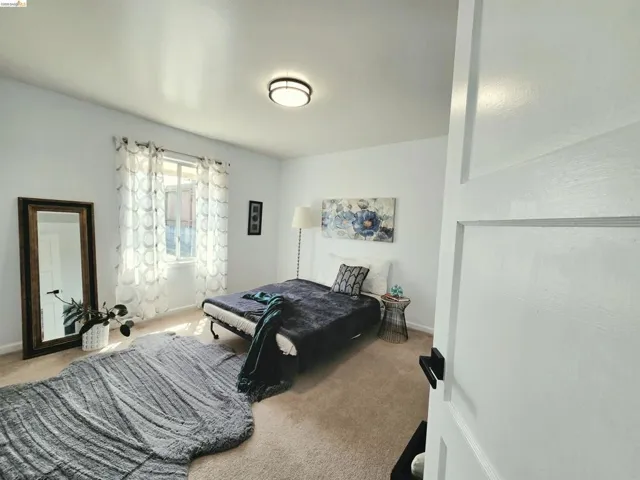 Carpeted room featuring a white paneled door with black hardware, a window with sheer curtains, recessed lighting, and white walls