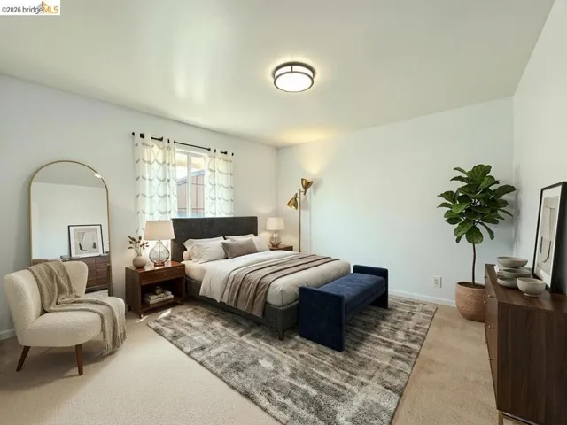 Spacious bedroom featuring light-colored carpeting, a window with natural light, and a ceiling-mounted light fixture. Virtual staging.