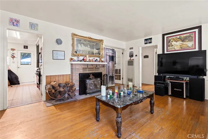 Another view of house with wall unit for heating, fireplace with insert, view of kitchen entrance and hallway entrance.
