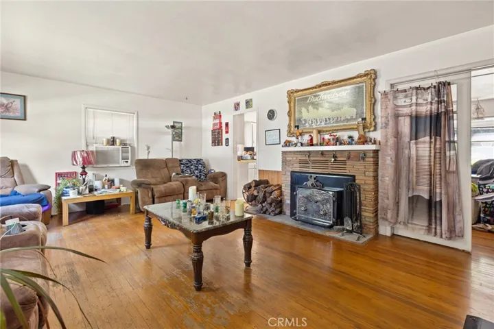 View of house with wood floors, woodstove insert fireplace, window a/c unit.