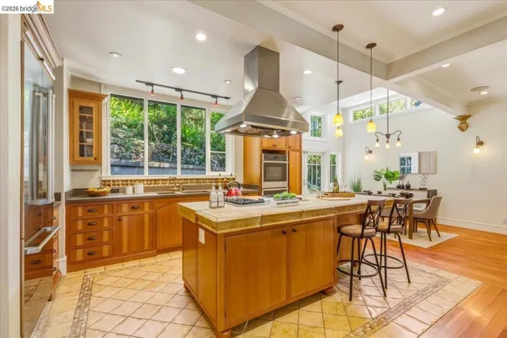 Kitchen featuring wood cabinetry, stainless steel appliances, and a central island with a tiled countertop