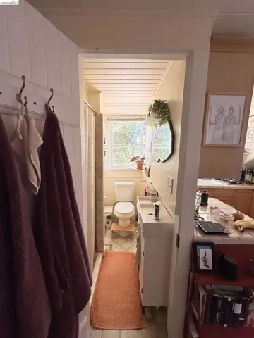 Compact bathroom featuring a white vanity with an integrated sink, a commode, and a window providing natural light