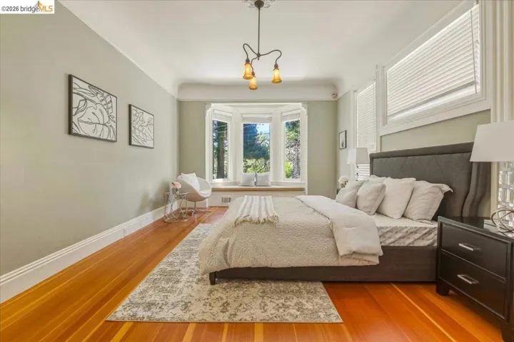 Room featuring a prominent bay window with a built-in bench, wood-finish flooring, and a decorative ceiling light fixture