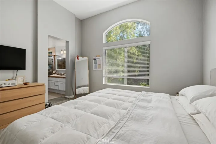 Primary bedroom features a large arched window, soft natural light, and a calming neutral color palette that creates a peaceful retreat.