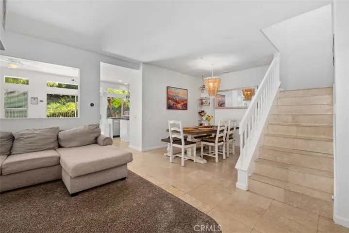 Bright and open living area with large windows, neutral finishes, and a seamless flow into the dining space and staircase.