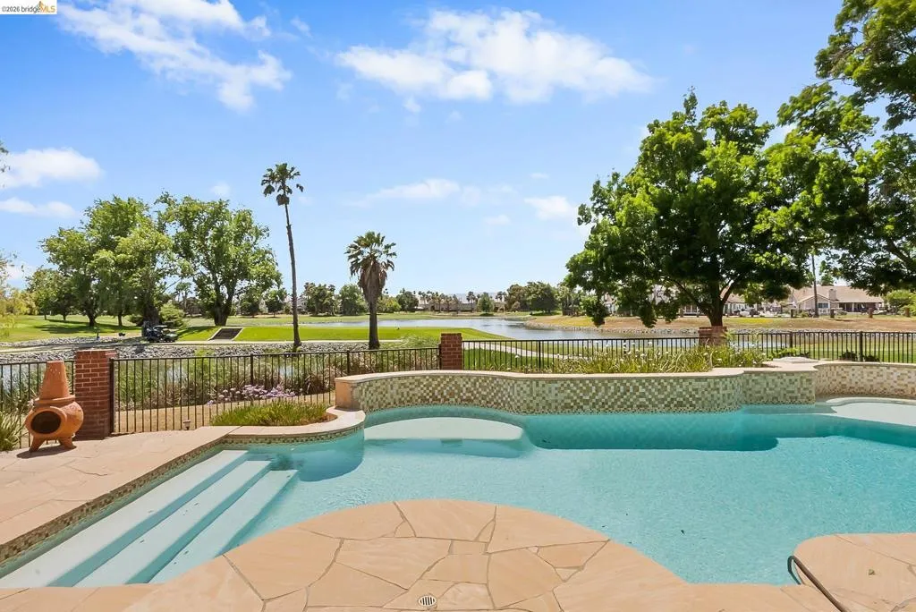 View of swimming pool with a water view and a patio