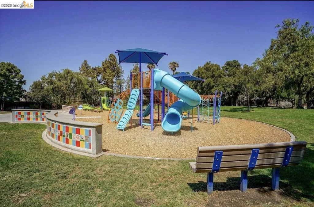 Community play area with a yard and view of wooded area