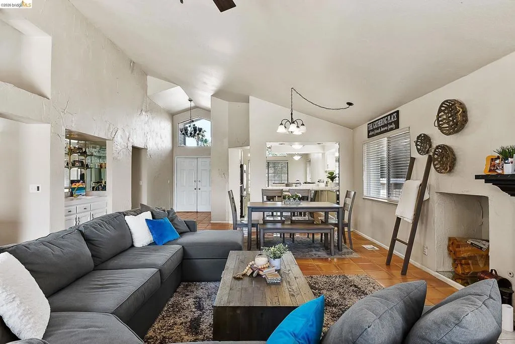 Tiled living area with a chandelier, high vaulted ceiling, and healthy amount of natural light