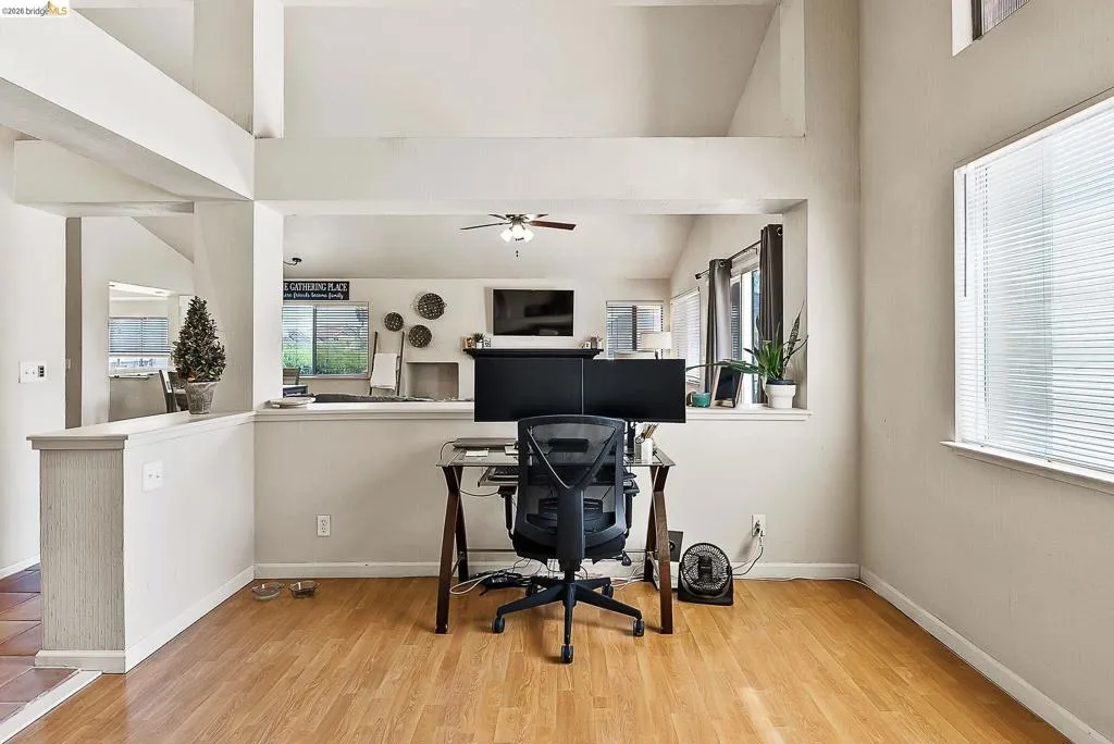 Office space with wood finished floors, lofted ceiling, plenty of natural light, and a ceiling fan