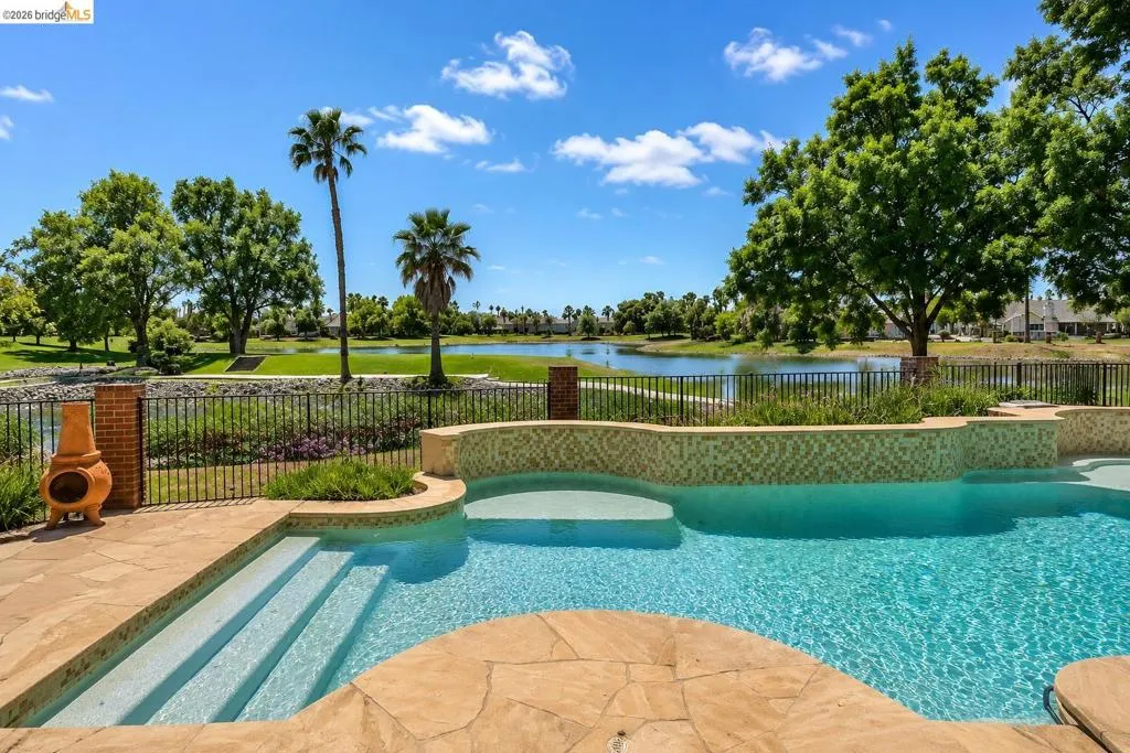 Expansive outdoor living area featuring a sparkling swimming pool with integrated steps, textured tile accents, and flagstone decking