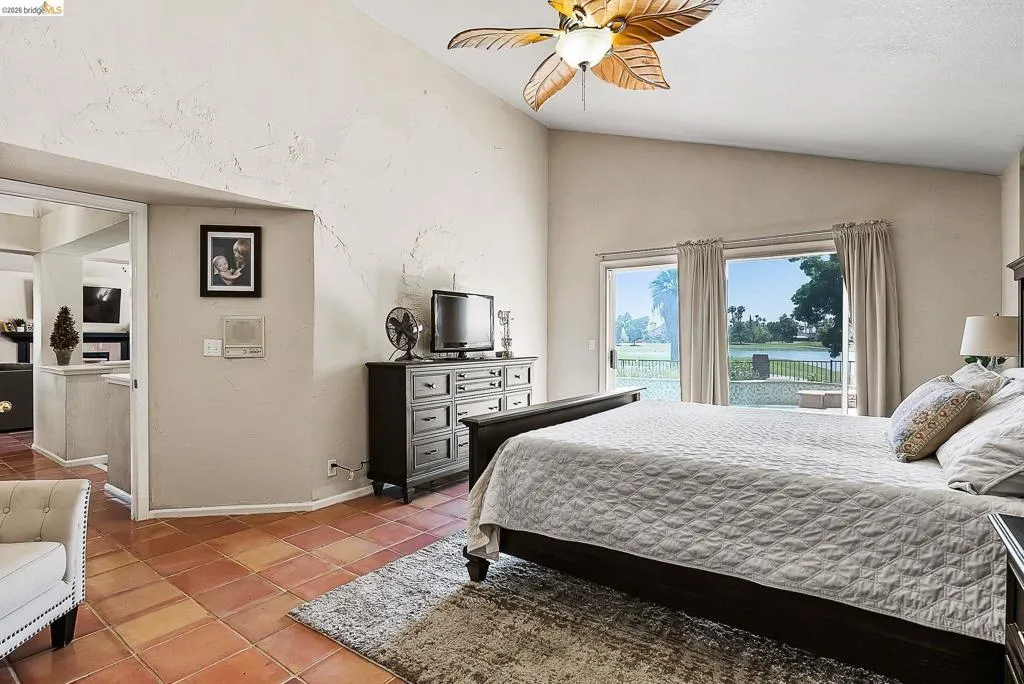 Tiled bedroom with lofted ceiling, access to outside, and ceiling fan