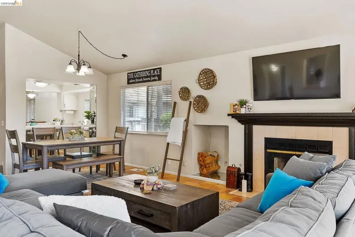 Living area with lofted ceiling, a chandelier, wood finished floors, and a fireplace