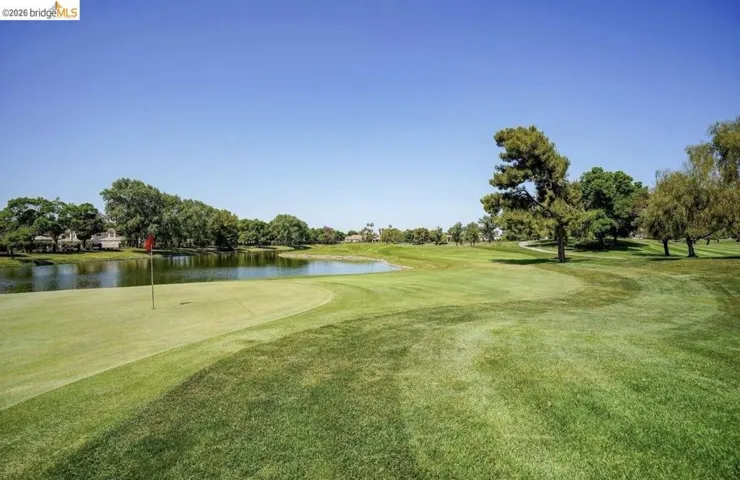 View of property's community with a water view, golf course view, a yard, and view of wooded area