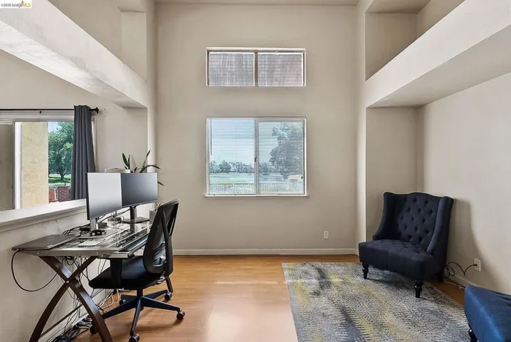 Office space with light wood-style floors and a towering ceiling