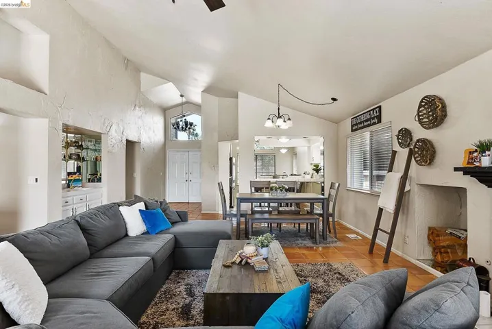 Tiled living area with a chandelier, high vaulted ceiling, and healthy amount of natural light