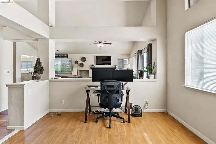 Office space with wood finished floors, lofted ceiling, plenty of natural light, and a ceiling fan