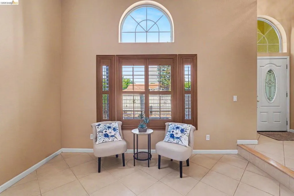 Arched transom window above a large window with plantation shutters