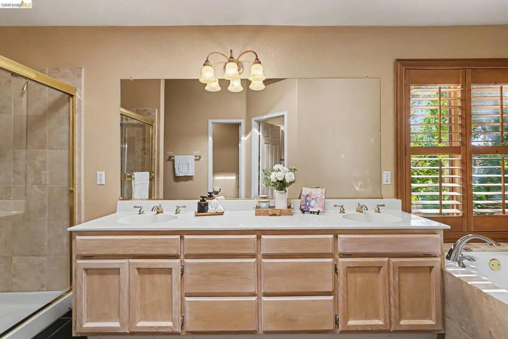 Bathroom vanity with dual undermount sinks, a white countertop, and extensive natural wood cabinetry