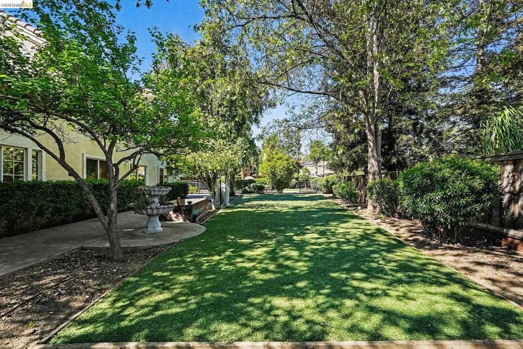 Expansive green lawn surrounded by mature trees, privacy landscaping, and a decorative fountain