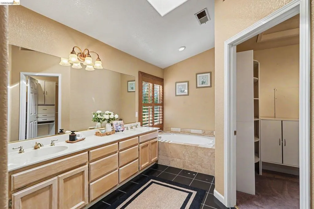 Dual vanity with integrated sinks, a large wall-mounted mirror, and a five-light fixture