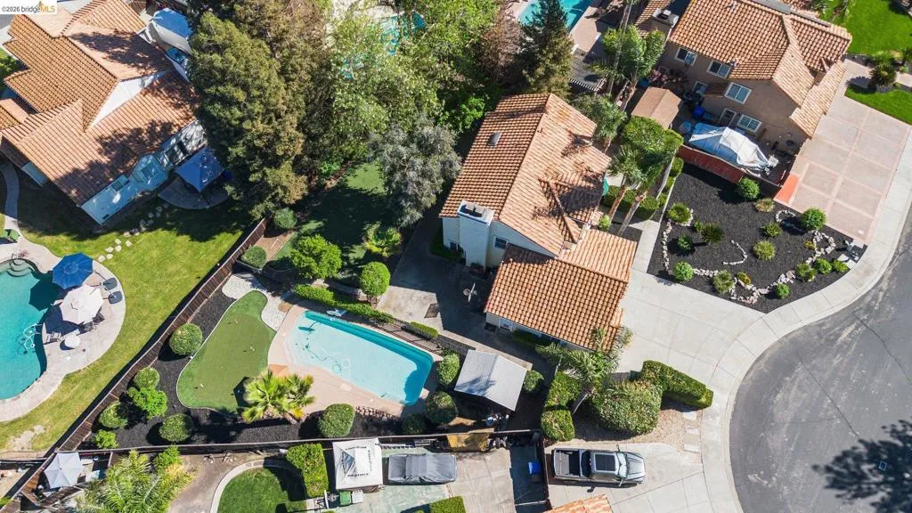 Rear yard featuring a swimming pool, manicured putting green, and mature landscaping