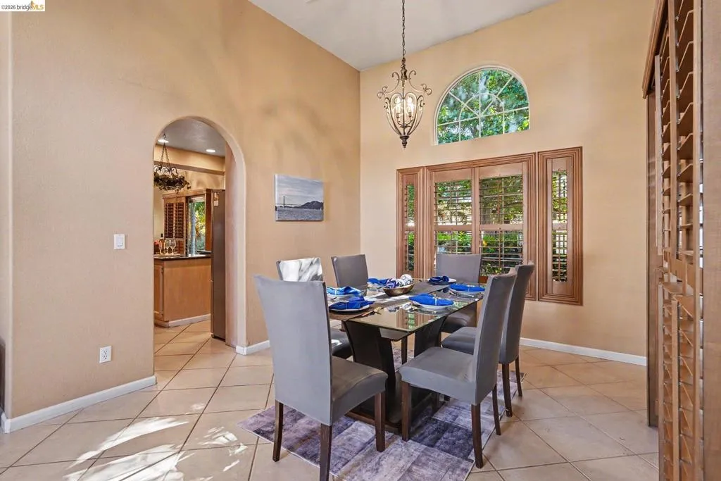 Dining area featuring vaulted ceilings, a decorative chandelier, and a large arched transom window