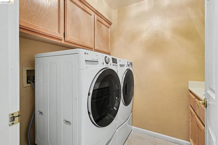 Laundry area with wood-finish cabinetry, tile flooring, and a built-in sink vanity