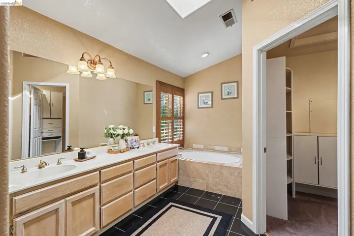 Dual vanity with integrated sinks, a large wall-mounted mirror, and a five-light fixture