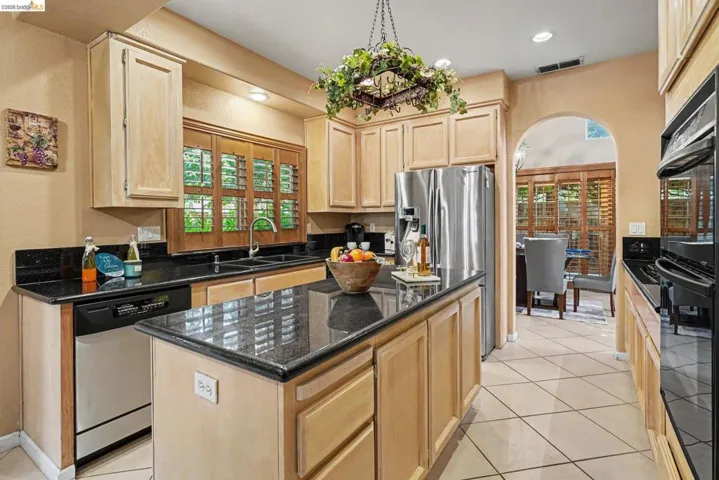 Kitchen featuring light wood cabinetry, black countertops, and a central island