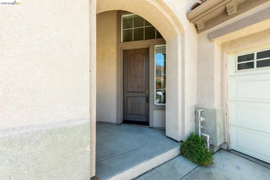 Arched entryway with a wood-finish front door and an adjacent sidelight with gridded panes