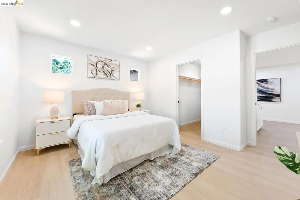 Bright bedroom featuring light wood-finish flooring, recessed lighting, and a window providing natural illumination