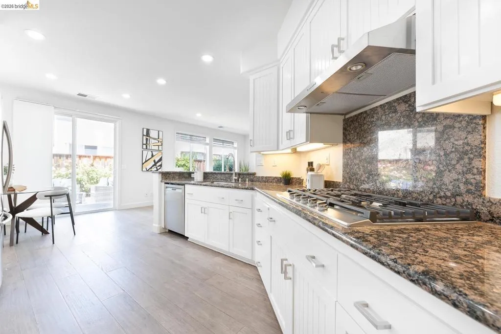 Gourmet kitchen featuring a stainless steel gas range, coordinating range hood, and granite countertops with a matching backsplash