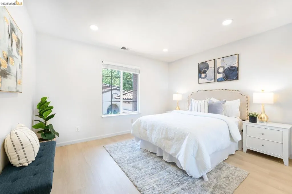 Recessed lighting illuminating light-toned walls and wood-finish flooring