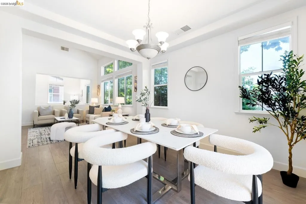 Open-concept dining area with wood-finish flooring and a contemporary chandelier