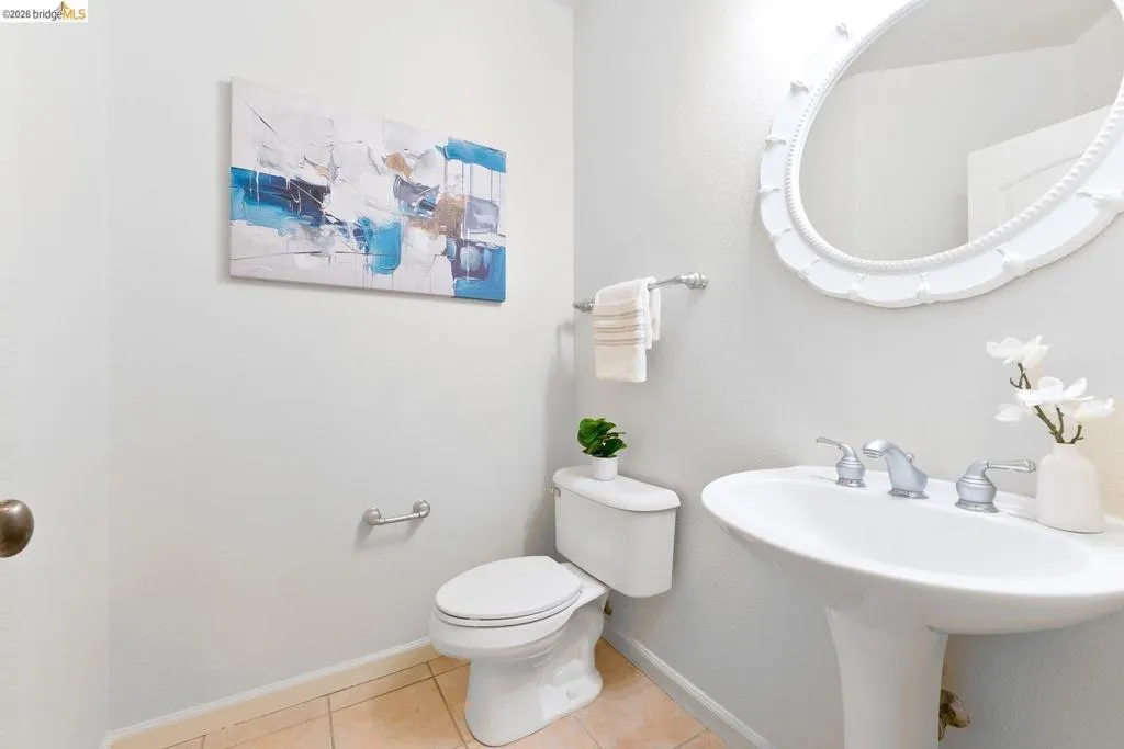 Pedestal sink with chrome fixtures and an ornate oval mirror