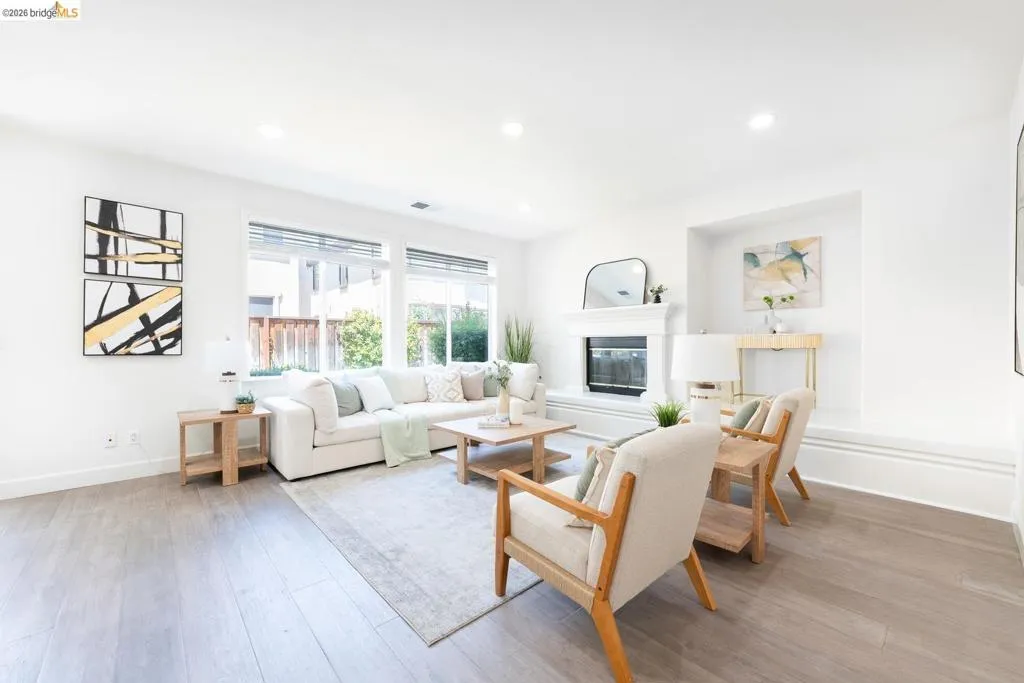 Spacious living area featuring light wood-finish flooring and extensive natural light from multiple windows