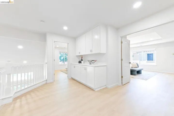 Upper-level hallway featuring wood-finish flooring, recessed lighting, and a built-in white cabinetry unit with a countertop