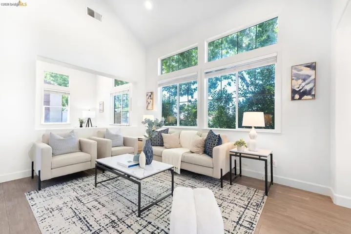 Spacious living area featuring high vaulted ceilings, expansive windows, wood-finish flooring, and a recessed wall opening