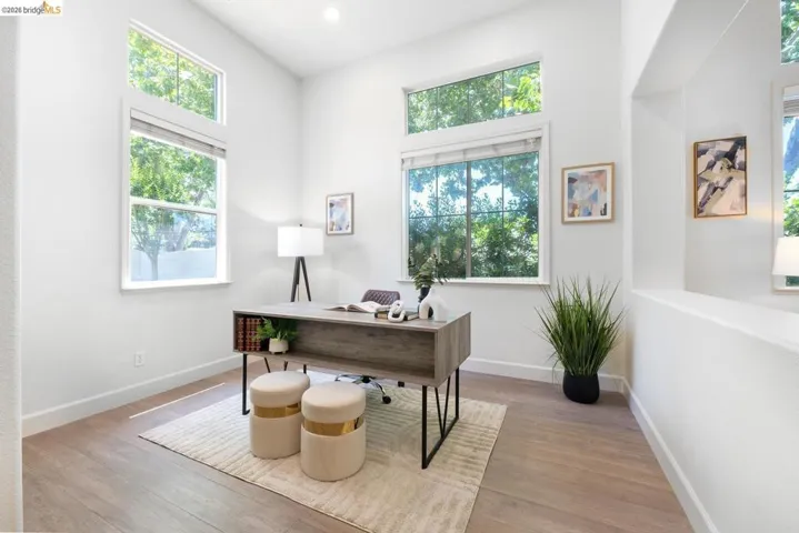 Room featuring high ceilings, multiple windows, recessed lighting, wood-finish flooring, and white baseboards