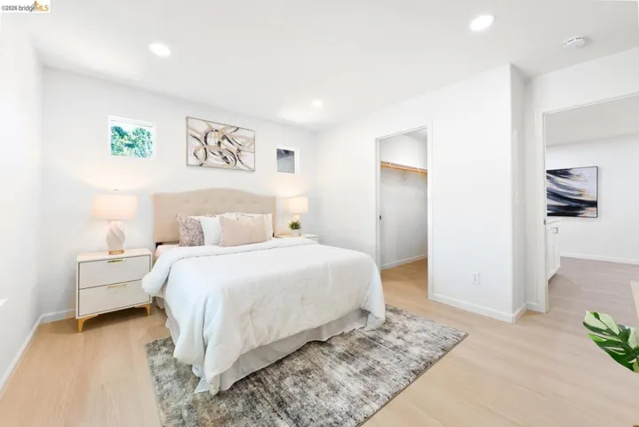Bright bedroom featuring light wood-finish flooring, recessed lighting, and a window providing natural illumination