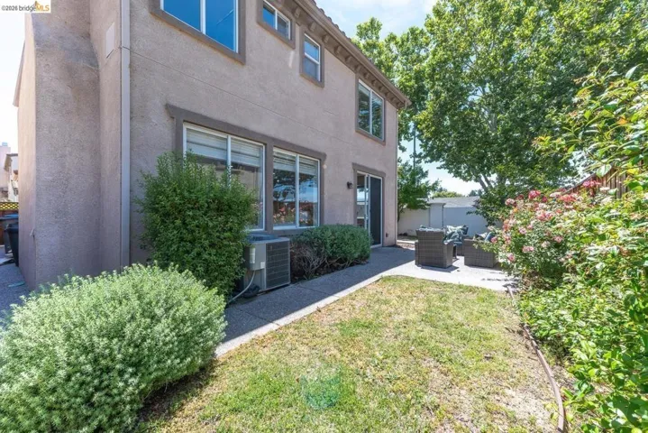 Private rear yard with concrete patio, mature trees, and established shrubbery