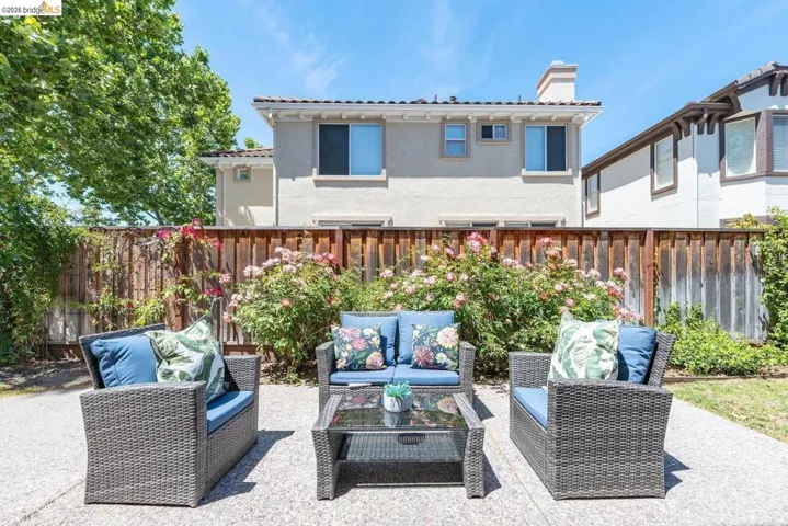 Expansive backyard patio featuring a concrete surface, a wood fence, and mature flowering shrubs