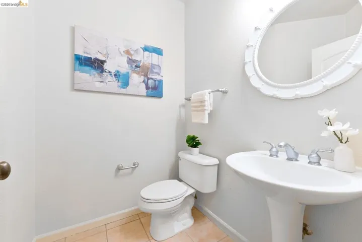 Pedestal sink with chrome fixtures and an ornate oval mirror