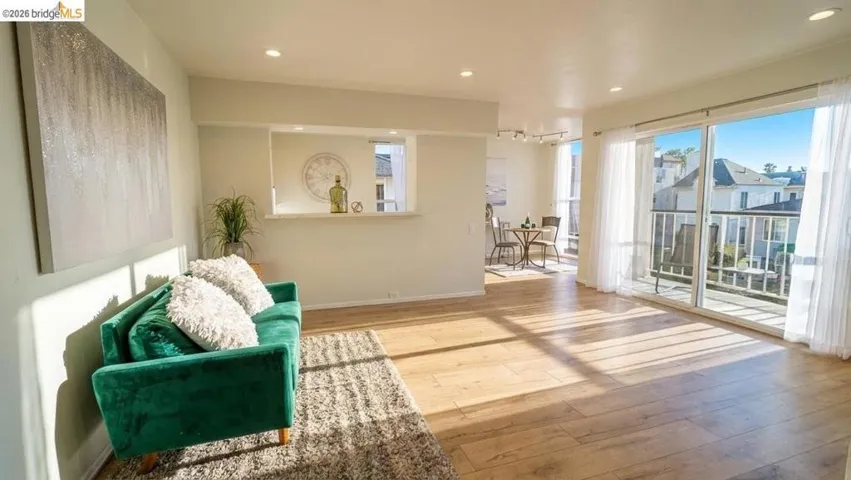 Spacious living area featuring wood-finish flooring, recessed lighting, and a pass-through window to the kitchen