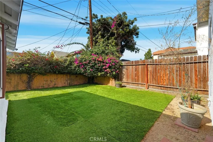 A resort-style backyard with its manicured lawn and mature trees and flowers perfect for children fun and entertainment