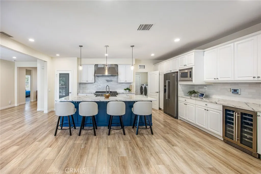 Exceptional chef's kitchen with an oversized quartz island, premium stainless steel appliances, custom cabinetry, and dual wine refrigerators