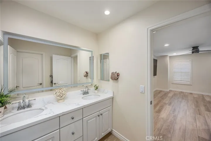 Dual-sink bathroom with quartz countertops and convenient access from adjoining bedrooms